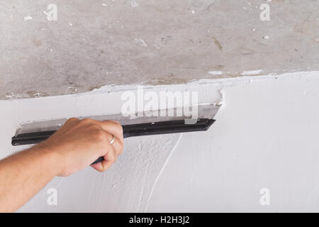 house improvement by worker puts finishing layer of stucco on the wall using a plastering trowel Stock Photo