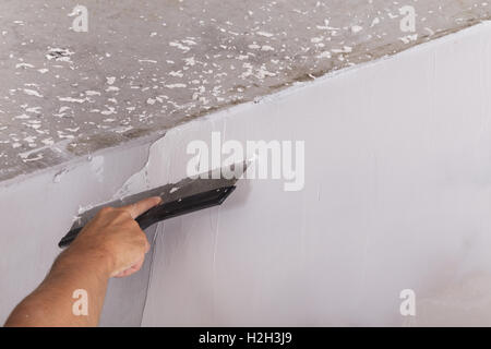 house improvement by worker puts finishing layer of stucco on the wall using a plastering trowel Stock Photo