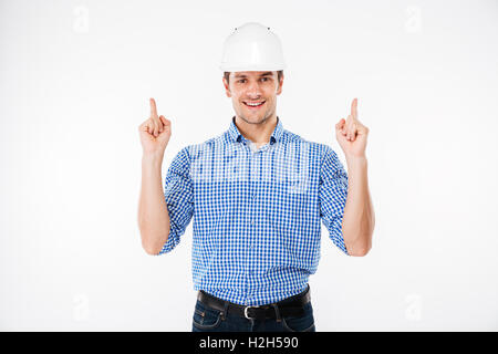 Cheerful young man architect in hard hat pointing up with both hands Stock Photo