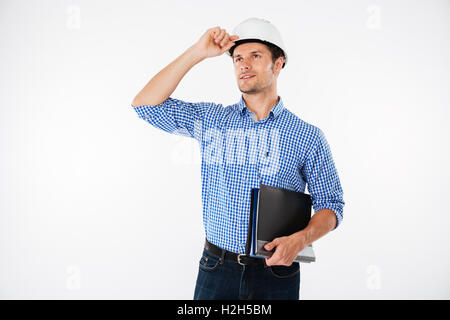 Handsome young man architect in building helmet standing and looking away Stock Photo