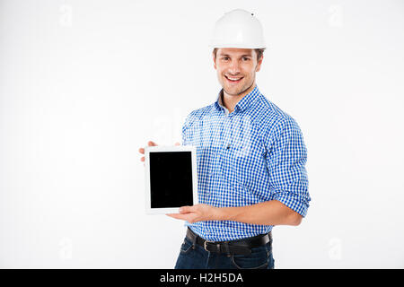 Happy young man architect in building helmet holding blank screen tablet Stock Photo