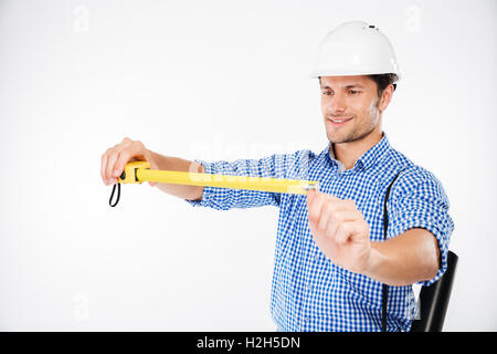 Happy young man building engineer in helmet using measuring tape Stock Photo