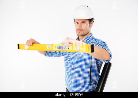 Serious young man building engineer in hard hat using spirit level Stock Photo