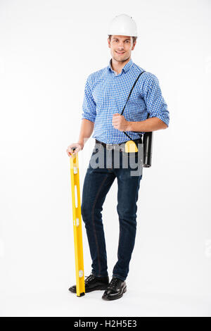 Cheerful young man builder in hard hat standing and holding spirit level Stock Photo