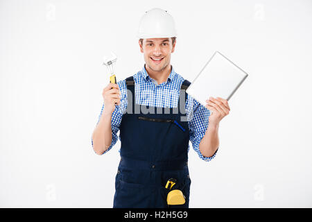Happy male builder showing thumb up and holding pc tablet isolated on a white background Stock Photo