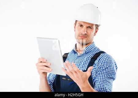 Thoughtful confused builder in helmet scratching his head and holding pc tablet isolated on a white background Stock Photo