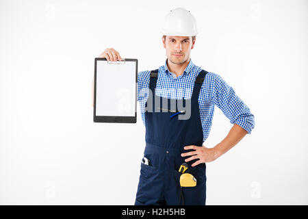 Serious handsome builder showing blank piece of paper on clipboard isolated on a white background Stock Photo