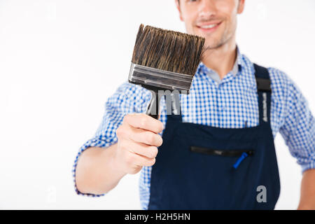 Cropped image of smiling male builder holding paint brush isolated on a white background Stock Photo