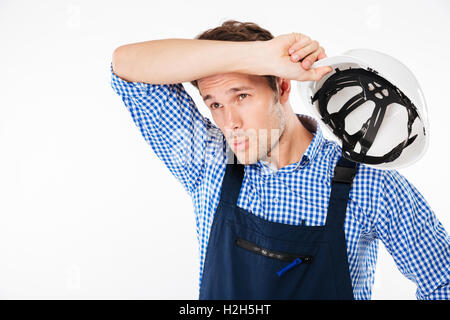 Portrait of tensed young constructor feeling exhausted after work isolated on a white background Stock Photo