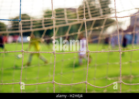 Soccer goal net with players in defocussed background Stock Photo
