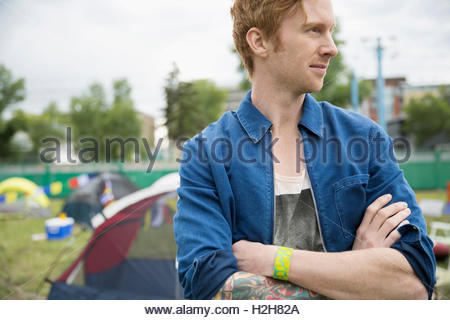 Portrait pensive young man with red hair looking away at summer music festival campsite