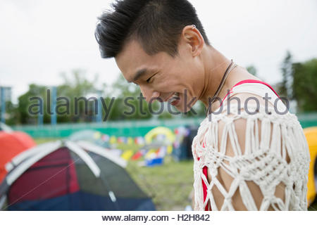 Laughing young man looking down at summer music festival campsite