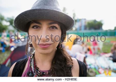Close up portrait confident young woman wearing fedora at summer music festival campsite