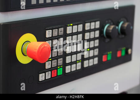 CNC machine control panel with emergency stop button on foreground. Stock Photo