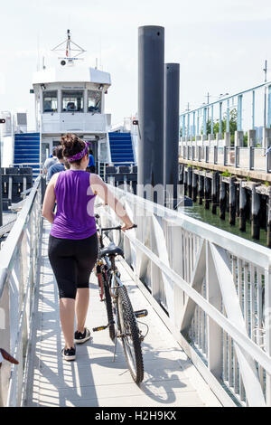 New York City,NY NYC Brooklyn,Brooklyn Bridge Park Pier 6,Yankee Pier,Governors Island Ferry,boat,adult adults,woman female women,bicycle,bicycling,ri Stock Photo