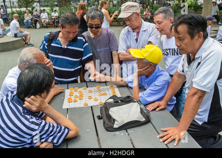 A group of Chinese Americans in Columbus Park in Chinatown, New York City playing Chinese Chess, also known as, Xiangqi. Stock Photo
