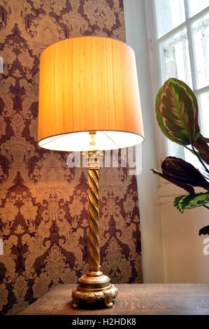 Old lamp of stay with a lampshade rest on wooden table in front of a window. Stock Photo