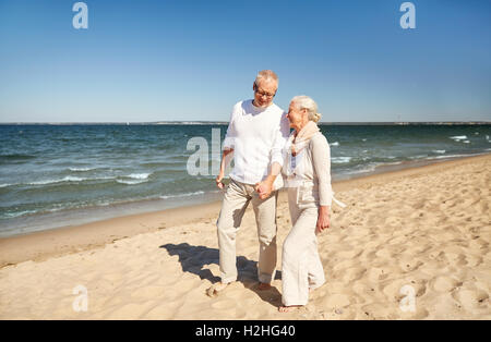 happy senior couple walking along summer beach Stock Photo