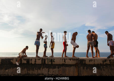 Kids in their bathing suits standing along the seawall about to go swimming along the Malecón in Central Havana, Cuba. Stock Photo