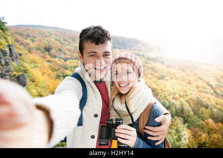 Young couple on a walk in autumn forest taking selfie Stock Photo