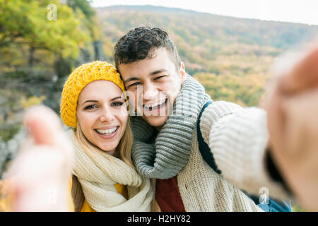 Young couple on a walk in autumn forest taking selfie Stock Photo