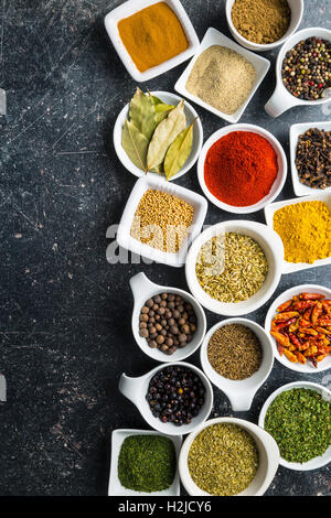 Various dried herbs and spices in ceramic bowls. Top view. Stock Photo