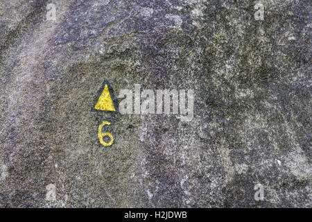 Rock texture of a boulder in the forest of Fontainebleau, with yellow, painted marks, indicating a climbing route Stock Photo