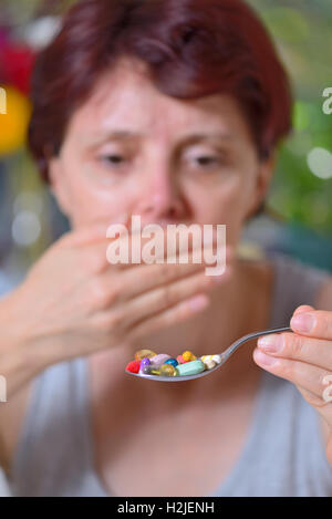 unwanted take pills  woman holding spoon with  pills Stock Photo