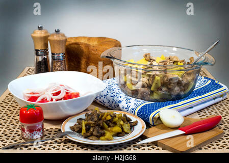 Fried potatoes with mushrooms, salad of fresh tomatoes and homemade bread for lunch Stock Photo