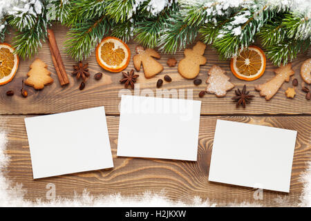 Christmas wooden background with photo frames, snow fir tree, spices and gingerbread cookies Stock Photo