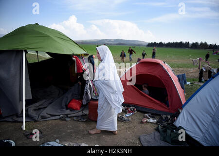 A refugee woman walks outisde a tent, at the refugee camp in the northern Greek village of Idomeni, at the Greek Macedonian border. Thousands of refugees and migrants were stranded for months at the Greek Macedonian border, at the refugee camp near the village of Idomeni, until the Greek government decided to evacuate the area. Stock Photo