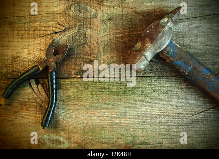 Old rusty pliers and hummer on old wooden table background. Old style photo Stock Photo