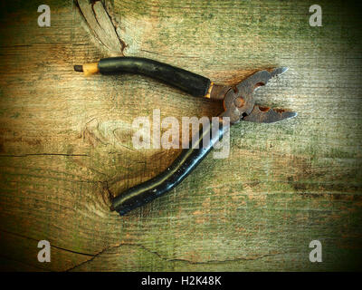 Old rusty pliers on old wooden table background. Old style photo Stock Photo