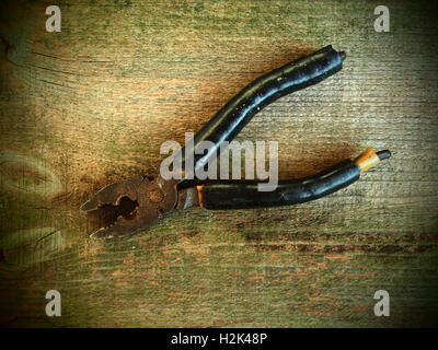 Old rusty pliers on old wooden table background. Old style photo Stock Photo