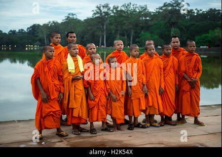 SIEM REAP, CAMBODIA - OCTOBER 30, 2014: A group of novice Buddhist monks in orange robes pose on the moat to Angkor Wat. Stock Photo