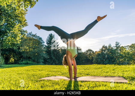 Handstand, young woman in sportswear doing workout on mat in park, Munich, Upper Bavaria, Bavaria, Germany Stock Photo