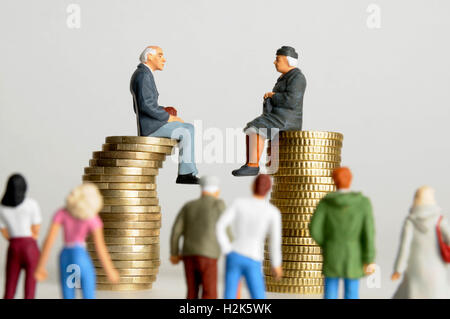 Elderly couple, figurines, sitting on stack of coins, watched by others, symbolic image for inheritance Stock Photo