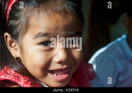 A four year old girl is smiling while riding on a bus in Tboung Khmum Province, Cambodia. Stock Photo