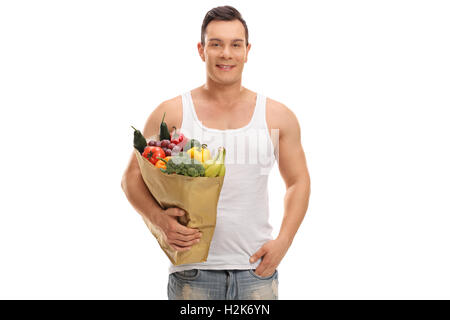 Smiling guy holding a shopping bag full of groceries isolated on white background Stock Photo