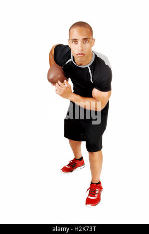 A young Jamaican football player in his black outfit standing for white background with his football under his arm. Stock Photo