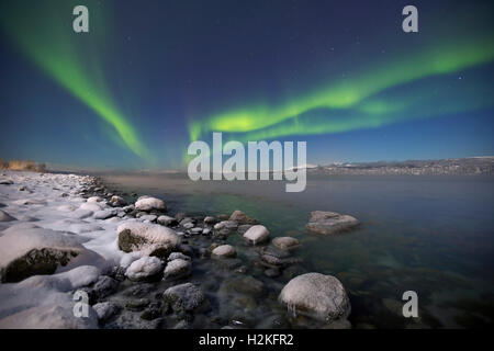The aurora borealis over a moonlit fjord in northern Norway in winter. Stock Photo