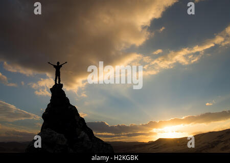 man on the top of a rock meeting sun Stock Photo