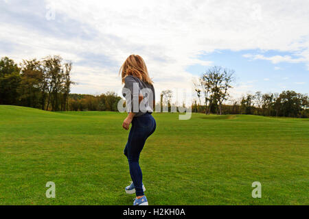 Blonde girl jumping with joy on a background of green lawn Stock Photo