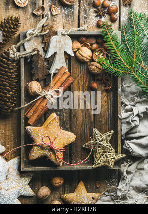 Gingerbread star shaped cookies, wooden angels, decorative stars, nuts and spices in wooden tray with sugar powder and decorativ Stock Photo