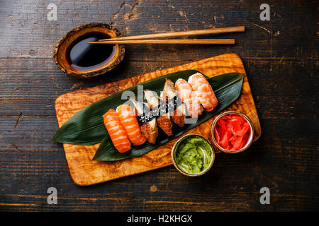 Nigiri Sushi Set on bamboo green leaf on olive wood board with soy sauce on wooden background Stock Photo