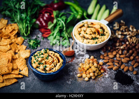 Spicy Pumpkin Hummus in two bowls and surrounded by chips, herbs, red bell pepper and nuts. Stock Photo
