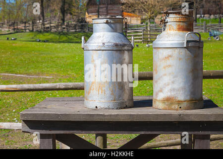 Two metal milk churns stand on wooden table Stock Photo