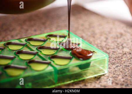 Pouring chocolate in mold, make praline Stock Photo