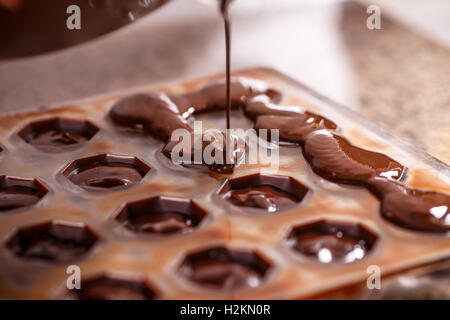 Pouring chocolate in mold, make praline Stock Photo