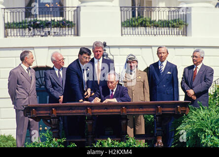 Minister of Foreign Affairs of Israel Shimon Peres puts his signature on the agreement during the signing ceremony of the historic Israeli-PLO Agreement, known as the Oslo 1 Accord, on the South Lawn of the White House in Washington, DC on September 13, 1993. Pictured, from left to right: From left to right are: Foreign Minister Andrei Kozyrev of Russia; Prime Minister Yitzhak Rabin of Israel; unknown aide; United States President Bill Clinton; Peres; Chairman Yasser Arafat of the Palestine Liberation Organization (PLO); US Secretary of State Warren Christopher; and Arafat aide Mahmoud Abbas. Stock Photo